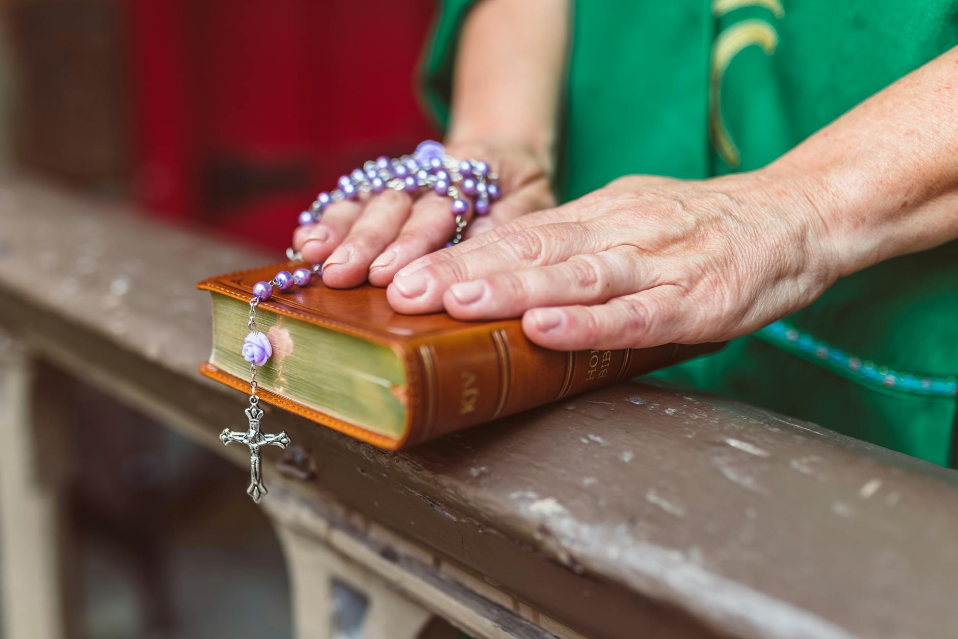 Dłonie oparte na Biblii z różańcem, modlitwa i duchowość