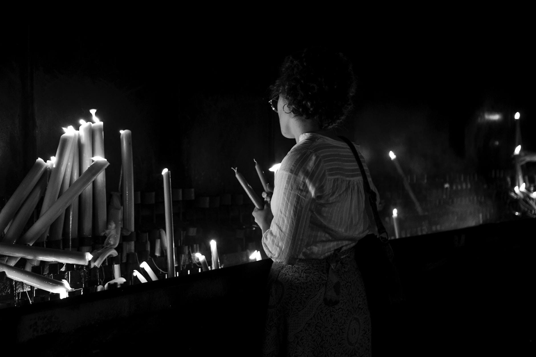 Kobieta zapala świece w sanktuarium jako znak modlitwy