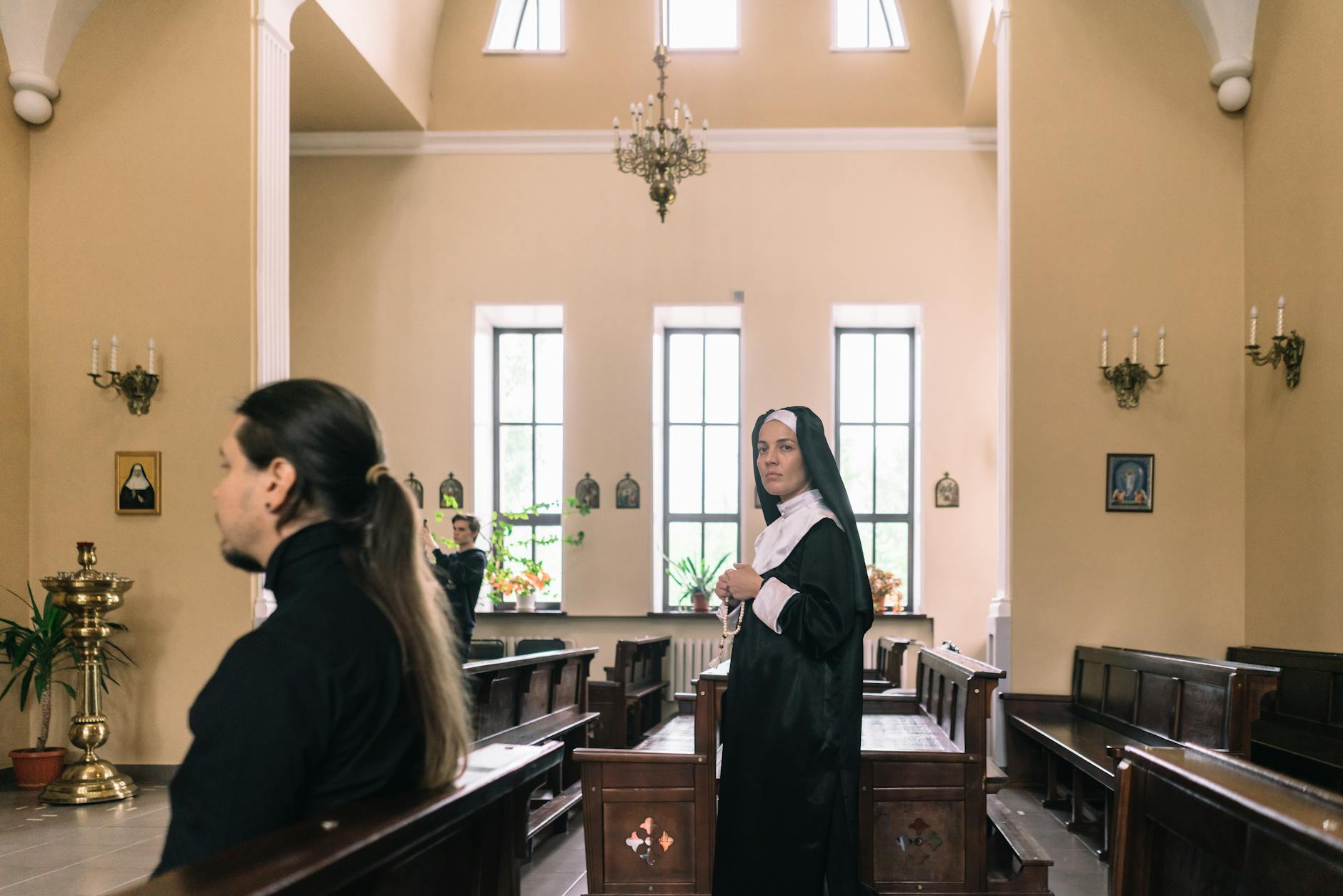 Zakonnica modląca się w jasnym kościele w świetle wpadającym przez okna