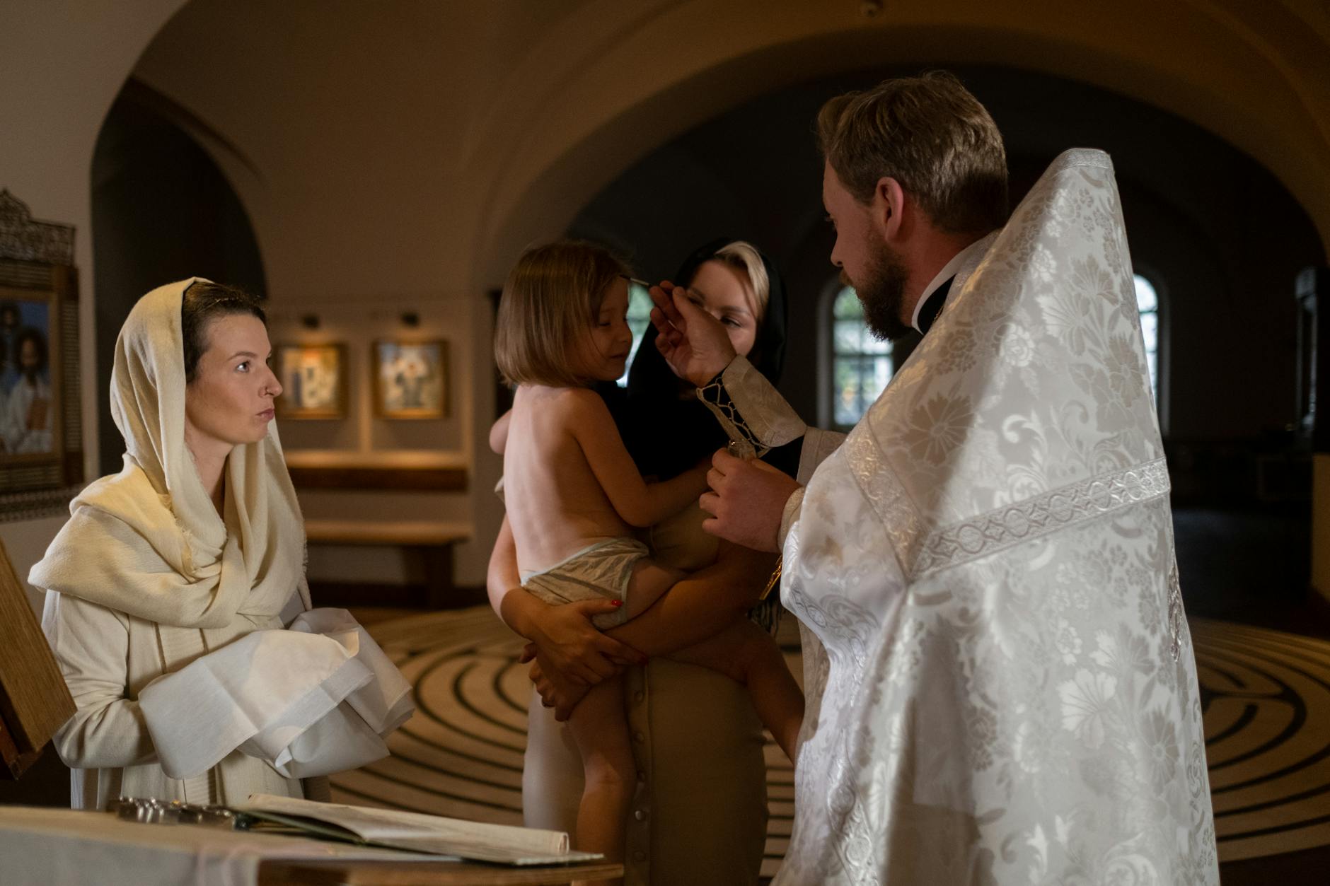 Kapłan udziela chrztu dziecku w kościele w obecności rodziny