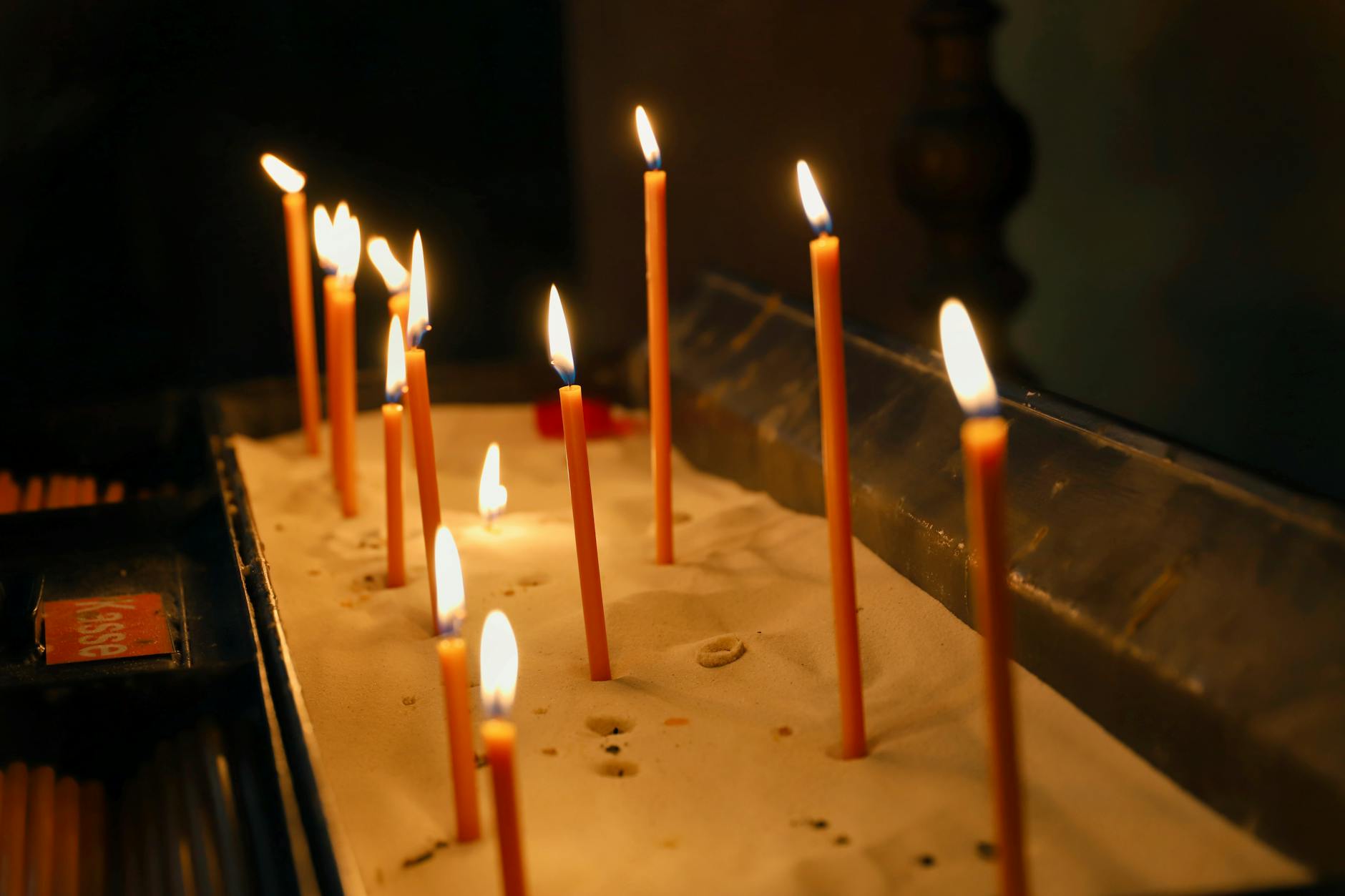 Płonące świece ustawione na piasku w kościele podczas nocnego czuwania