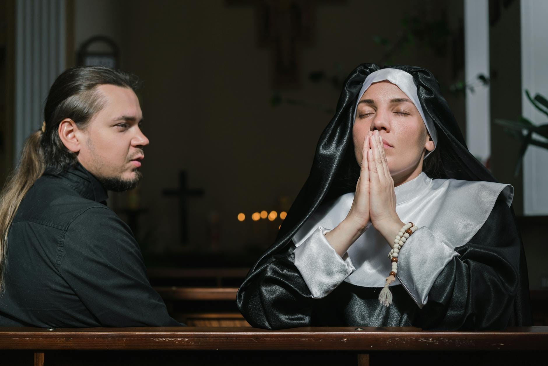 Zakonnica modląca się w kościele obok mężczyzny pogrążonego w modlitwie
