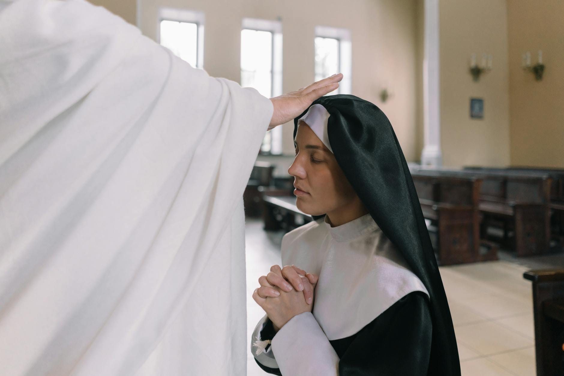 Zakonnica przyjmująca błogosławieństwo kapłana w kościele