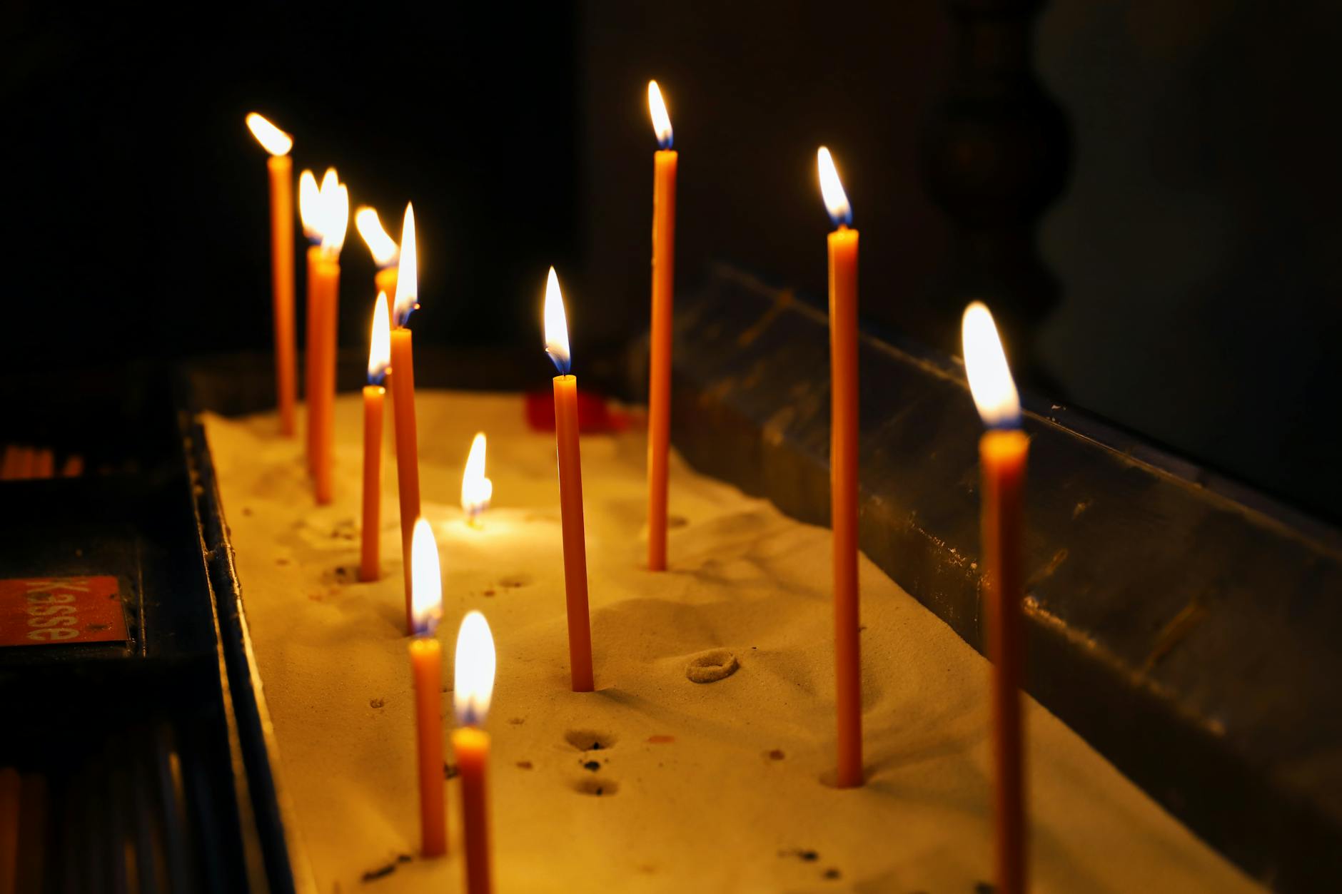 Zapalone świece w piasku w zaciemnionym sanktuarium