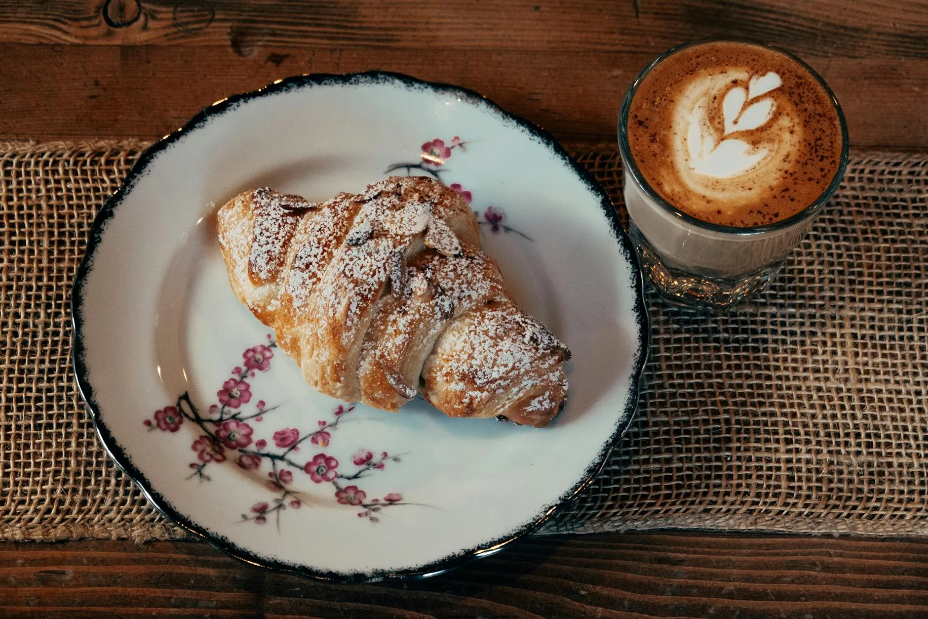 Croissant i cappuccino na rustykalnym drewnianym stole