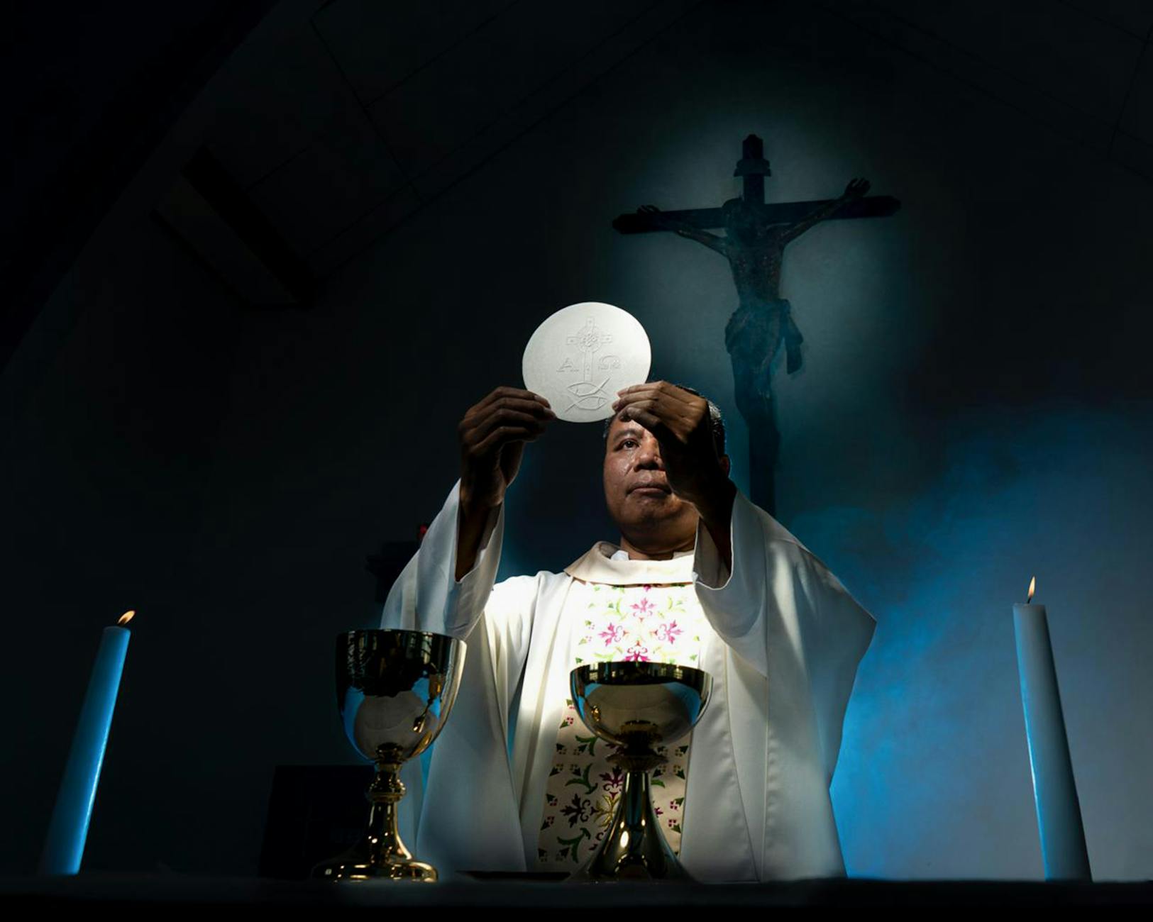 Kapłan unosi hostię podczas uroczystej Mszy świętej w kościele