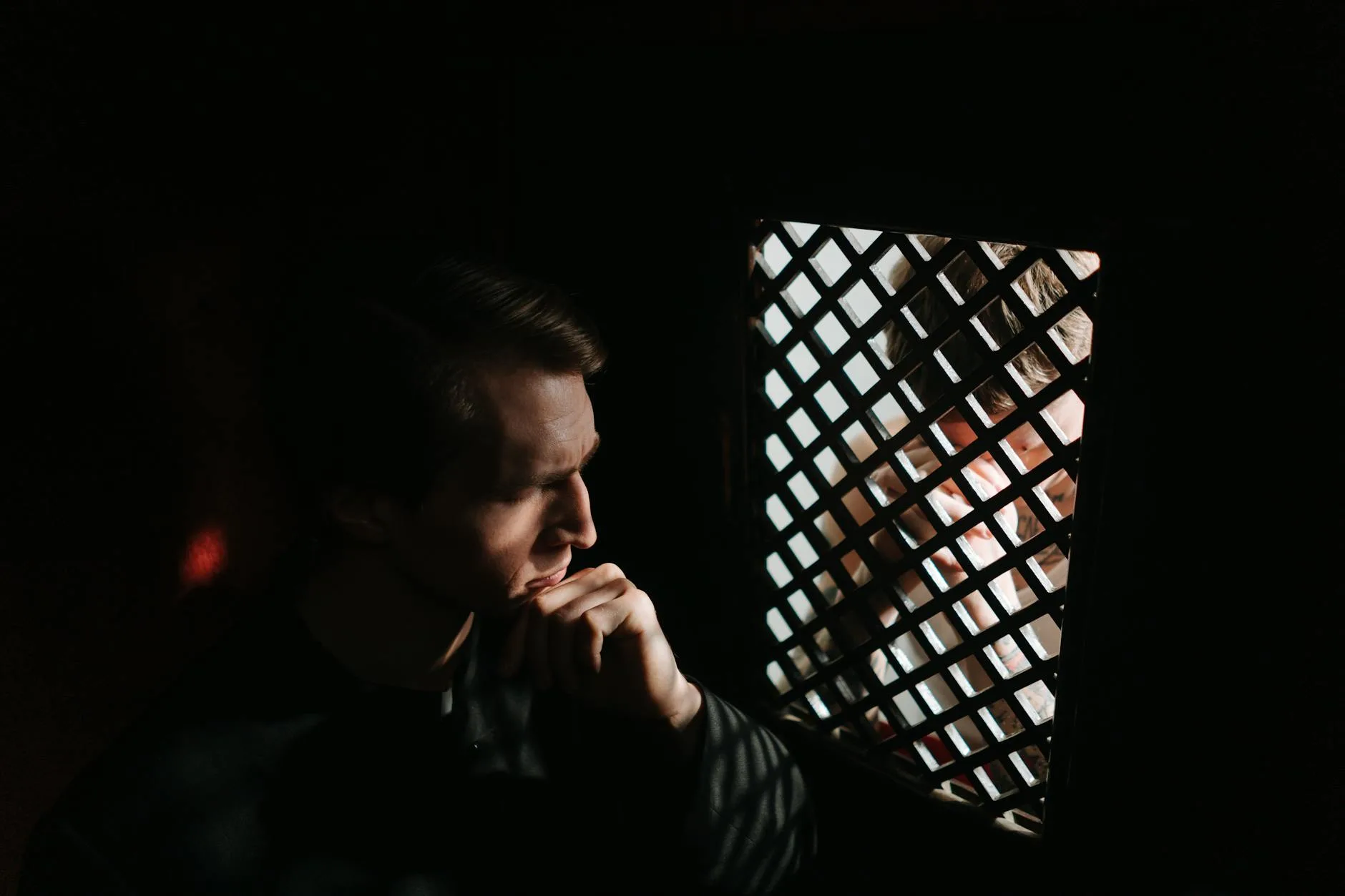 Mężczyzna pogrążony w spowiedzi w półmroku kościoła