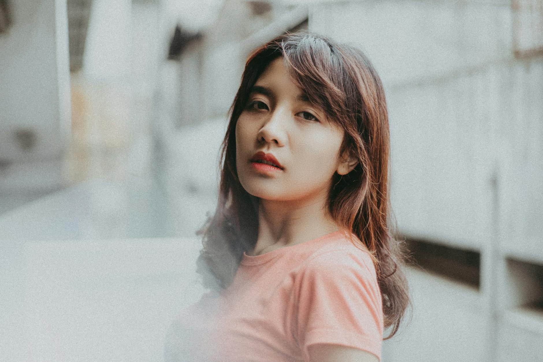 Młoda kobieta o pewnym wyrazie twarzy na tle miejskiej zabudowy