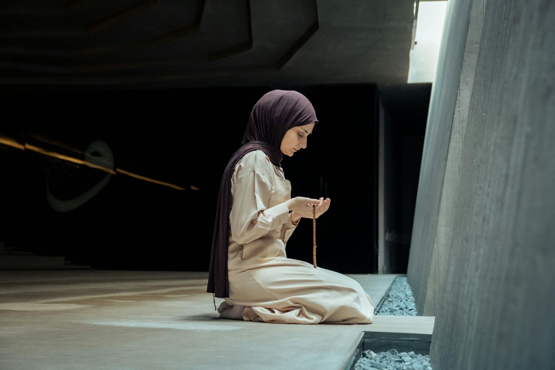 Muzułmanka w hidżabie modli się w ciszy, trzymając różaniec w dłoniach