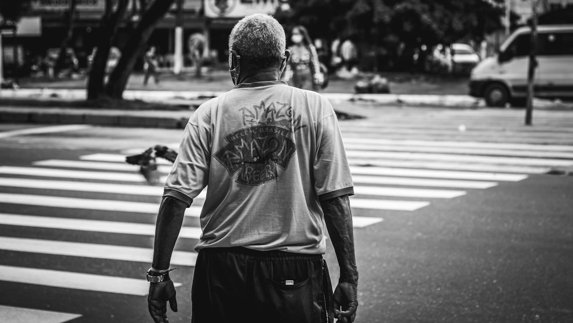 Czarno-białe zdjęcie mężczyzny przechodzącego przez pasy w mieście