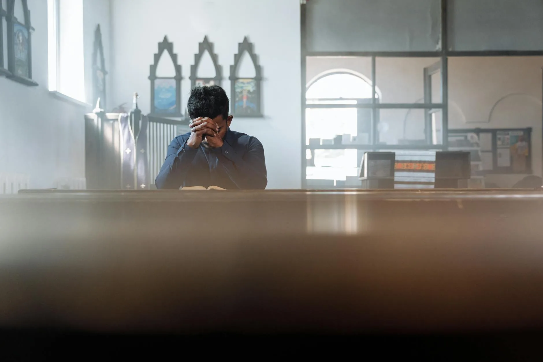 Mężczyzna modlący się w słonecznym pokoju, szukający swojego patrona