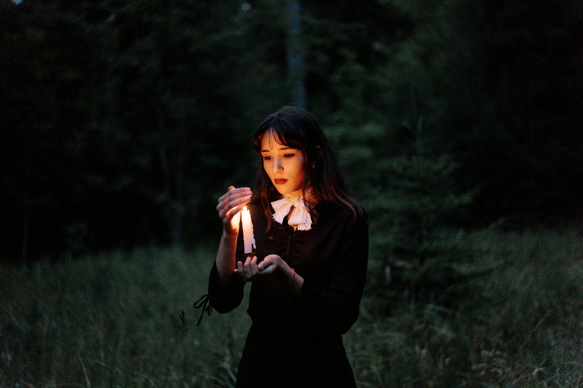 Św. Łucja: światło wiary silniejsze niż prześladowanie Młoda kobieta z zapaloną świecą idzie przez ciemny las