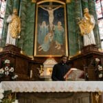 Oktawa Wielkanocy: dlaczego Kościół świętuje osiem dni i co to zmienia? Kapłan głosi kazanie przy ozdobnym ołtarzu w kościele z witrażami
